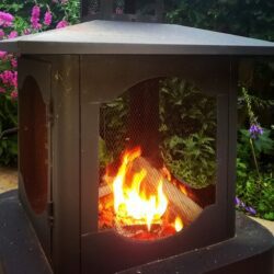 Fire pit with flames in garden setting.